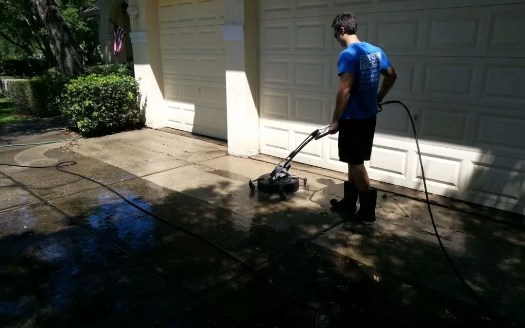 Tampa Bay Window Cleaning technician pressure washing a concrete driveway with a surface cleaner